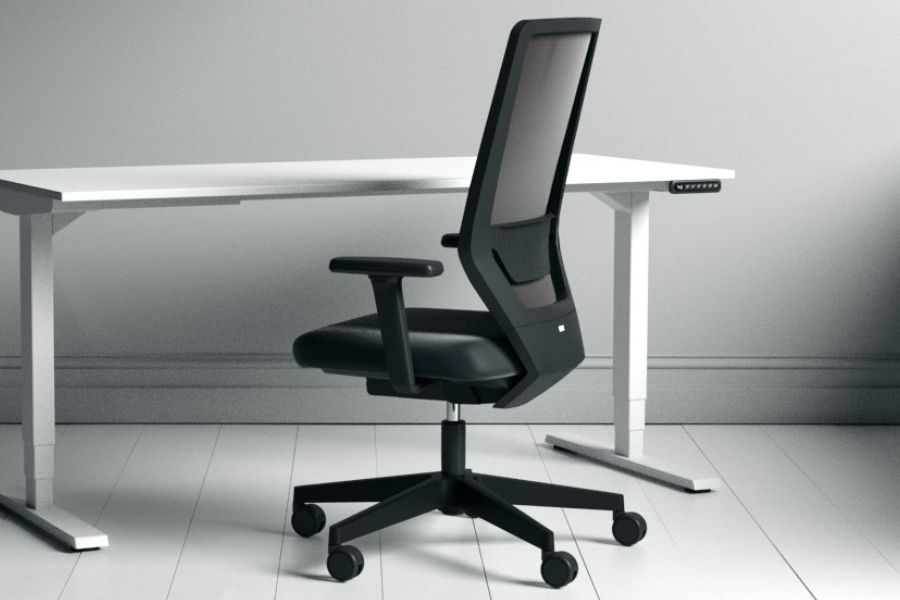 Schwarzer ergonomischer Bürostuhl an einem weißen Schreibtisch in minimalistischer Umgebung