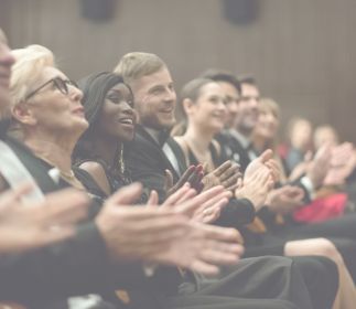 Eine Gruppe von Menschen, die applaudieren, während sie auf Stühlen sitzen.