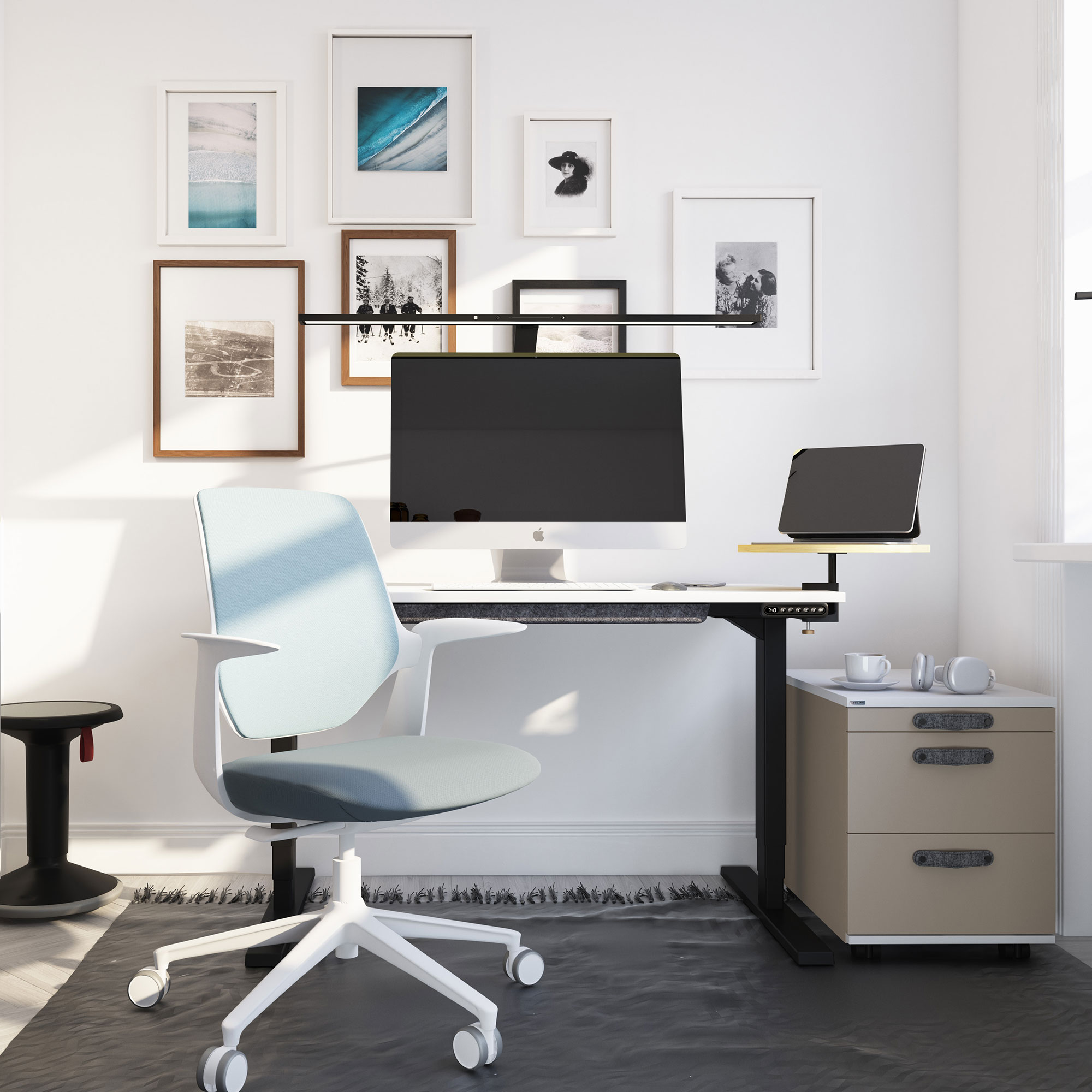 Ein modernes Büro mit einem Computer, einem Tablet, einem Schreibtisch, einem blauen Stuhl und dekorativen Bildern an der Wand.