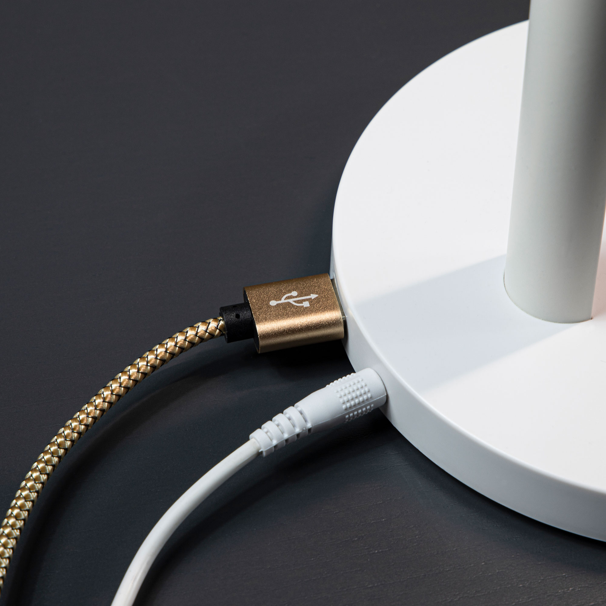 Ein USB-Kabel und ein Audiokabel, die an einer weißen Tischlampe angeschlossen sind.