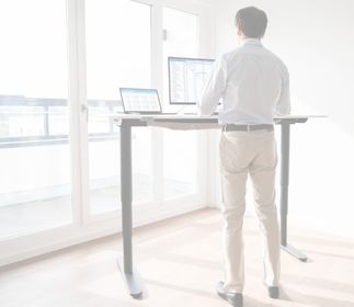 Eine Person steht an einem Stehtisch und arbeitet an einem Computer.