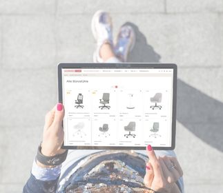 Eine Person, die ein Tablet hält, zeigt eine Website mit verschiedenen Bürostühlen.