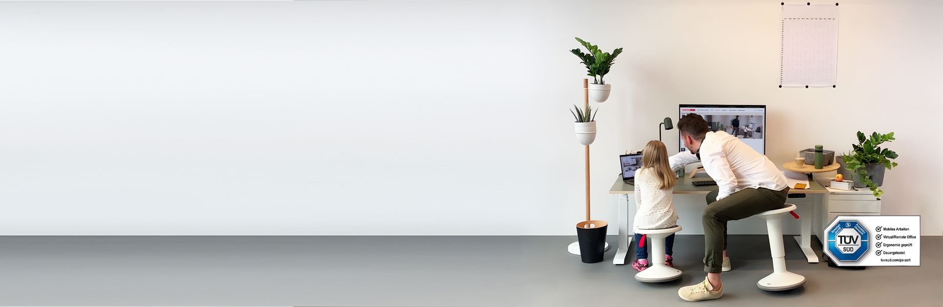 Vater und Tochter arbeiten gemeinsam am Schreibtisch in einem modernen Homeoffice mit Pflanzen.