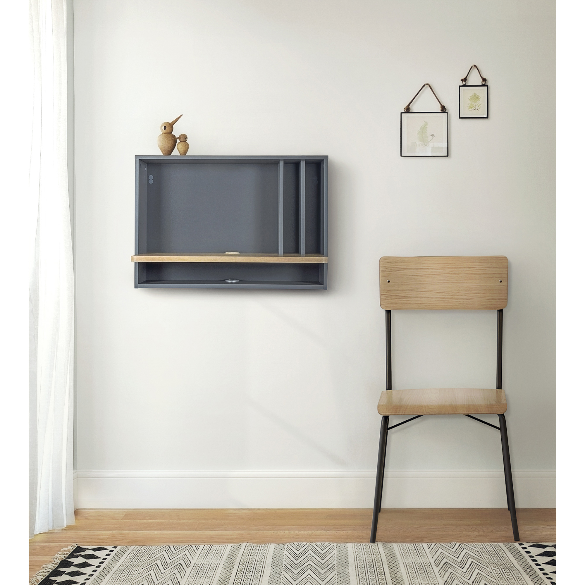 Ein minimalistisches Zimmer mit einem grauen Wandregal, einer Holzablage, einem kleinen Deko-Vogel und einem Holzstuhl. An der Wand hängen zwei kleine Bilderrahmen.