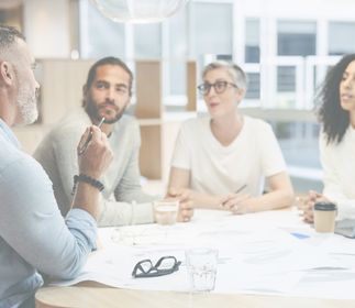 Vier Personen sitzen an einem Tisch im modernen Büro.