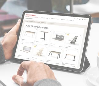 Eine Person, die auf einem Tablet eine Webseite mit verschiedenen Schreibtischen durchblättert.
