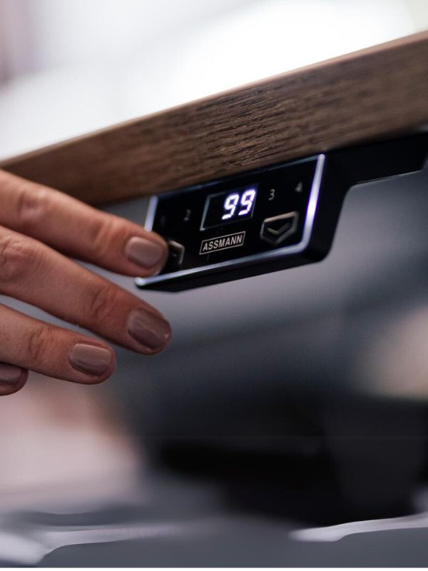 Detailaufnahme einer Hand, die das digitale Bedienfeld eines ASSMANN-Schreibtischs einstellt